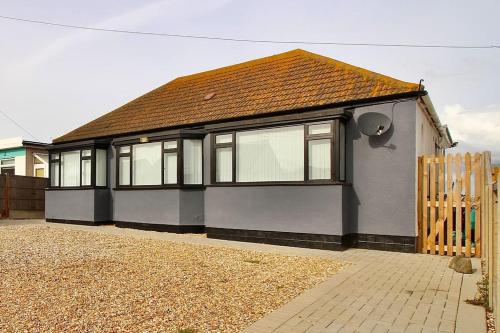 a house with a brown roof and a fence at BRiSYL BEACH HOUSE, with amazing changing views! in Kent