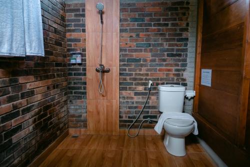 uma casa de banho com um WC e uma parede de tijolos em The Dukuh Retreat em Tabanan