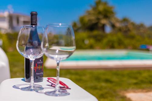 a bottle of wine and two wine glasses on a table at Casa Limiuni in Buonfornello