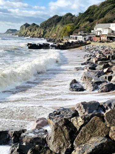 a beach with rocks and the ocean and houses at Centrally located "Spring Cottage" Perfect Ventnor Holiday Home in Ventnor