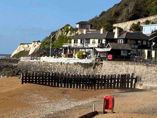 a building on the beach next to the ocean at Centrally located "Spring Cottage" Perfect Ventnor Holiday Home in Ventnor
