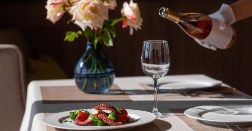 a table with a plate of food and a glass of wine at Oak Leaf Residences in Budva