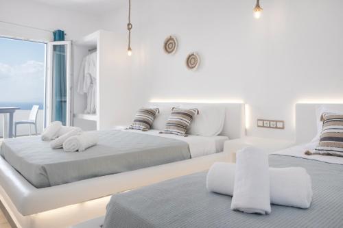 biała sypialnia z 2 łóżkami i stołem w obiekcie Feel Breeze w mieście Mykonos