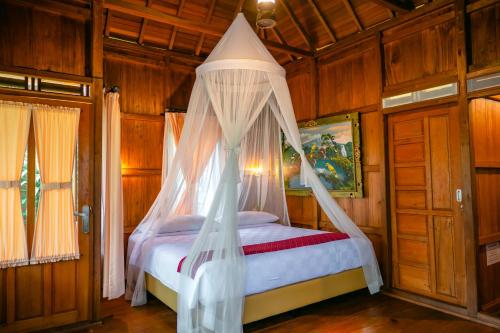 a bedroom with a bed with a canopy at The Dukuh Retreat in Tabanan