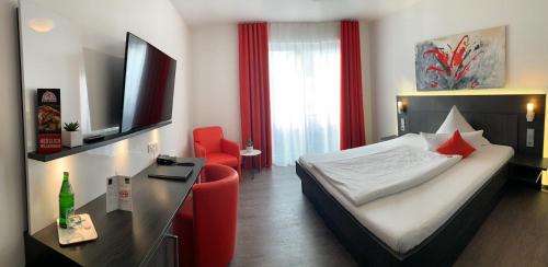 a hotel room with a bed and a red chair at Campushotel in Hagen