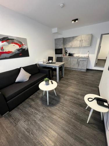 a living room with a couch and tables and a kitchen at Campushotel in Hagen