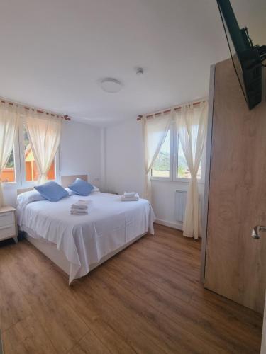 a white bedroom with a large bed and windows at Maile Apartamentos in Potes