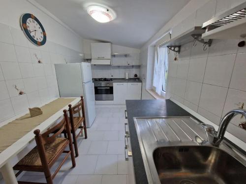 a kitchen with a sink and a clock on the wall at La casetta di Flo in Montecosaro