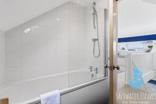 a white bathroom with a tub and a shower at Seaway Garden in Paignton