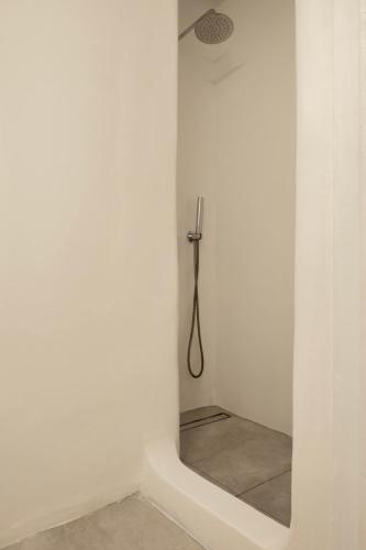 a shower in a white room with a mirror at Feel Breeze in Mikonos