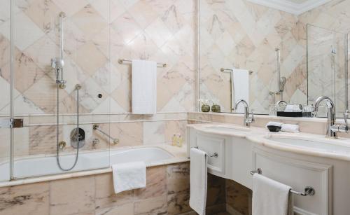 a bathroom with two sinks and a tub and a shower at Althoff Grandhotel Schloss Bensberg in Bergisch Gladbach
