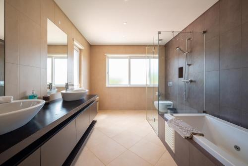 Un baño con dos lavabos, una bañera y una ducha. en VILLA SIBLING 2, en Vilamoura