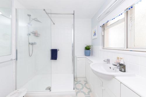 a white bathroom with a shower and a sink at Secluded Spacious Garden Suite in Chichester