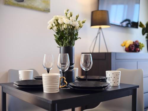 a dining room table with glasses and a vase of flowers at Villa Łeba Pokoje & Apartamenty in Łeba