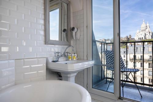 a bathroom with a tub and a sink and a balcony at Le Regent Montmartre by Hiphophostels in Paris