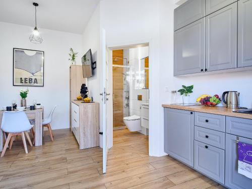 a kitchen with white cabinets and a table and a dining room at Villa Łeba Pokoje & Apartamenty in Łeba