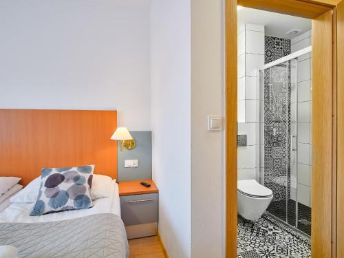 a hotel room with a bed and a shower at Villa Łeba Pokoje & Apartamenty in Łeba