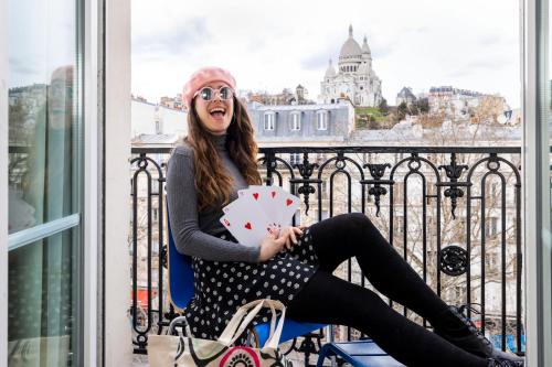 a woman sitting on a balcony holding a polka dot umbrella at Le Regent Montmartre by Hiphophostels in Paris