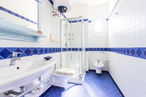 a blue and white bathroom with a toilet and a sink at Resort Cala La Luna in Favignana