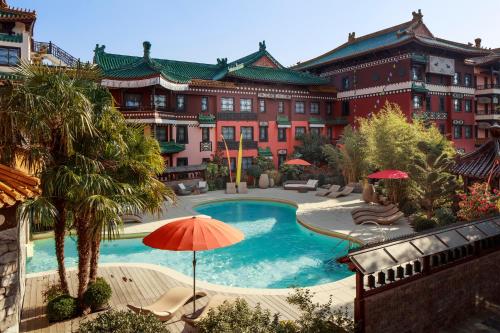 a large building with a swimming pool and an umbrella at Hotel Ling Bao, Phantasialand Erlebnishotel in Brühl