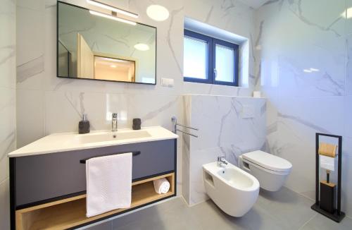 Un baño con lavabo, inodoro y espejo. en Apartments Paola & Karla with pool, en Krk