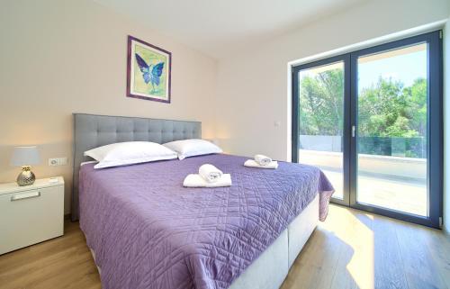 Un dormitorio con una cama morada con toallas encima. en Apartments Paola & Karla with pool, en Krk