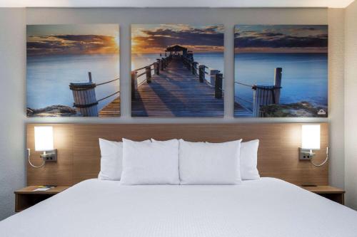 a bedroom with a bed and a painting of a pier at Days Inn & Suites by Wyndham Commerce in Commerce
