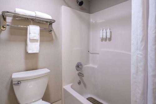 a bathroom with a toilet and a shower with towels at Days Inn & Suites by Wyndham Commerce in Commerce