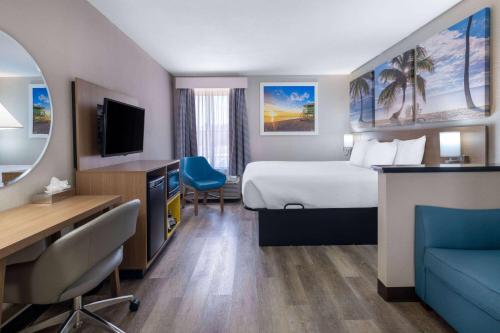 a hotel room with a bed and a desk and a television at Days Inn & Suites by Wyndham Commerce in Commerce