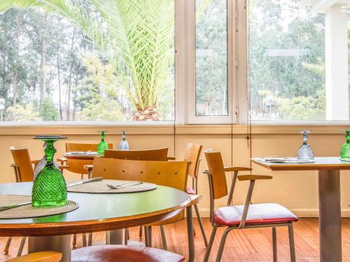un ristorante con tavoli e sedie con vasi verdi sopra di Hotel ibis Porto Sul Europarque a Santa Maria Da Feira