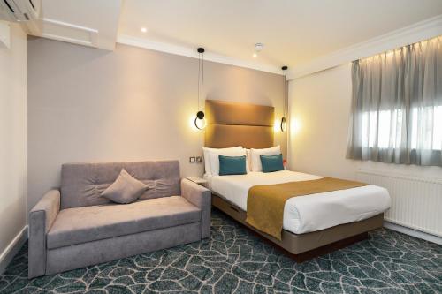 a hotel room with a bed and a couch at Queens Park Hotel in London