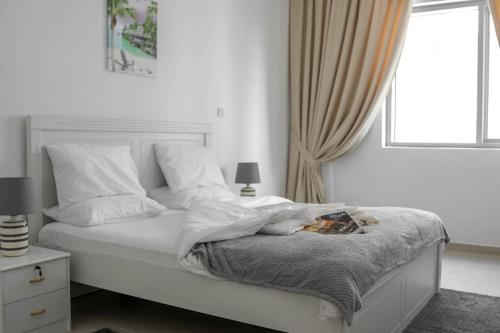 Dormitorio blanco con cama y ventana en BEST 2 Bedroom Apartment Beach Front (Sea View), en Abu Dabi