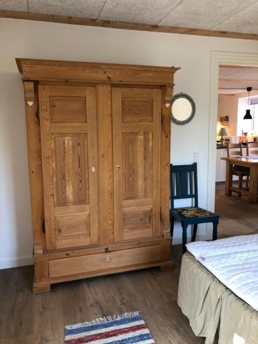 a wooden cabinet in a bedroom with a bed at Nordgården - ferie på landet in Skibby