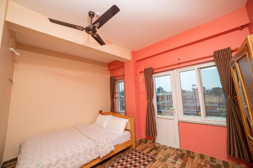 Schlafzimmer mit orangefarbenen Wänden und Deckenventilator in der Unterkunft Subedi Apartment in Pokhara