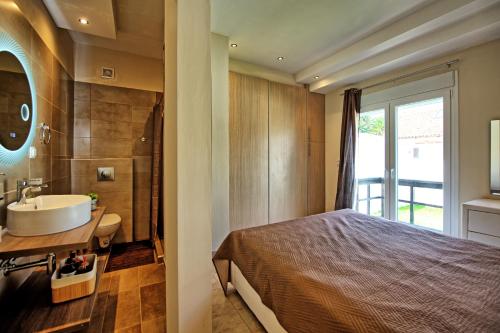 a bedroom with a bed and a bathroom with a sink at Beach Villa Christina by PosarelliVillas in Acharavi
