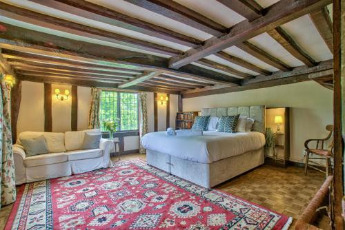 a bedroom with a bed and a couch and a rug at Ashfield Place Farm by Group Retreats in Stowmarket