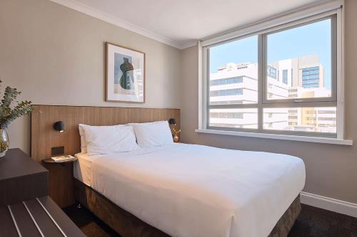 a bedroom with a large white bed and a window at Pensione Hotel Perth in Perth