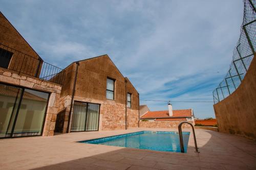 a swimming pool in front of a brick building at Chalês - Maria Alva in Marialva