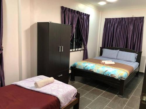 una camera con due letti e un armadio con asciugamani di Ceria Homestay Putatan a Putatan