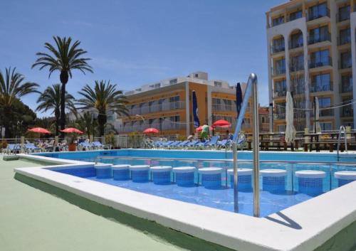 uma piscina num resort com cadeiras e guarda-sóis em Hostal Gami Adults Only em Cala Ratjada