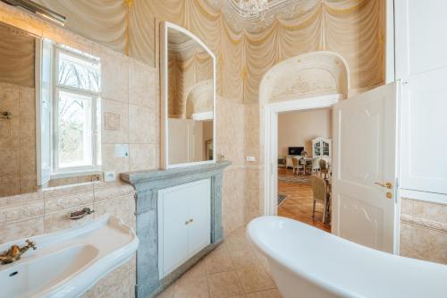 ein Badezimmer mit einer Badewanne, einem Waschbecken und einem Spiegel in der Unterkunft Zamek Hradek u Susice in Hrádek