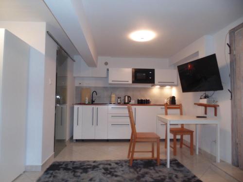 eine Küche mit einem Tisch und Stühlen sowie einem TV in der Unterkunft Krowoderska 63A in Krakau