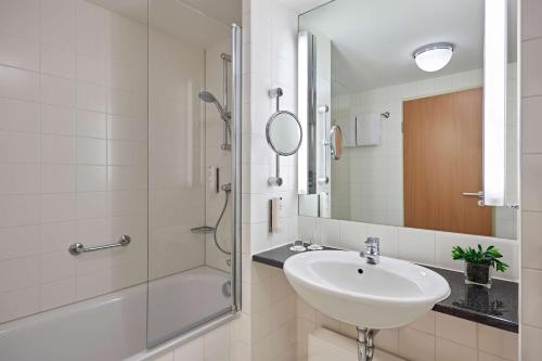 a white bathroom with a sink and a shower at Lindner Hotel Cologne Am Dom, part of JdV by Hyatt in Cologne