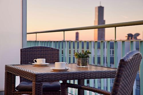 a table with two chairs and two cups on a balcony at Lindner Hotel Cologne Am Dom, part of JdV by Hyatt in Cologne