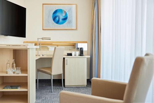 a hotel room with a desk and a television at Lindner Hotel Cologne Am Dom, part of JdV by Hyatt in Cologne