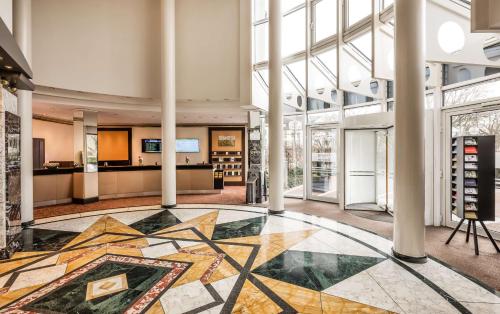 eine Lobby mit Mosaikboden und großen Fenstern in der Unterkunft Lindner Hotel Dusseldorf Airport, part of JdV by Hyatt in Düsseldorf
