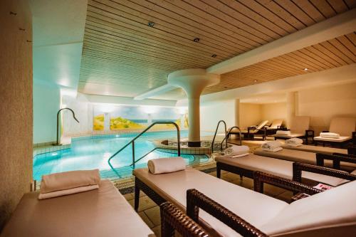een hotel met een zwembad en tafels en stoelen bij Lindner Hotel Sylt in Wenningstedt