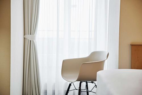 a white chair sitting in front of a window at Lindner Hotel Dusseldorf Airport, part of JdV by Hyatt in Düsseldorf