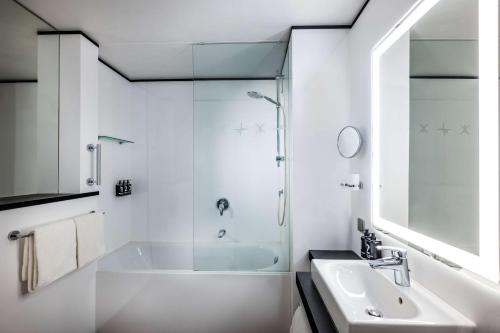 a white bathroom with a shower and a sink at Lindner Hotel Dusseldorf Airport, part of JdV by Hyatt in Düsseldorf