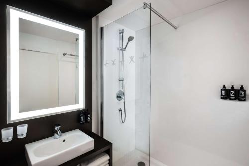 a bathroom with a sink and a shower with a mirror at Lindner Hotel Dusseldorf Airport, part of JdV by Hyatt in Düsseldorf